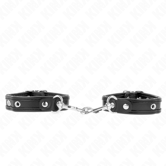 Braccialetti neri regolabili con borchie KINK WRIST RESTRAINT, 16-22 cm, 2 cm di larghezza, mostrati su una superficie.